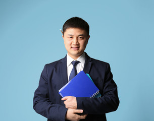 Handsome young Asian teacher on light background