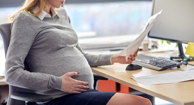 pregnant businesswoman reading papers at office