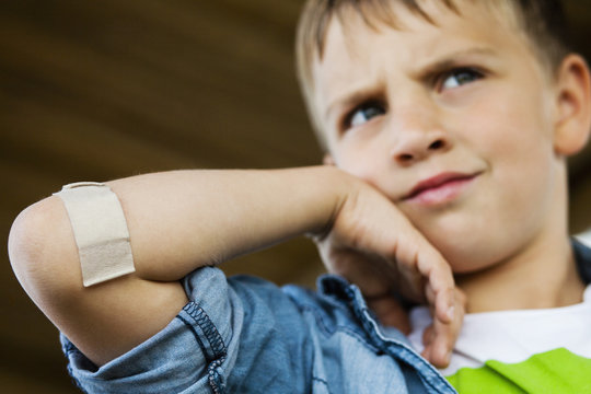 Low angle view of boy with adhesive bandage on arm