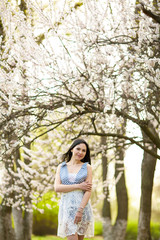 Young woman in blooming apricot garden.