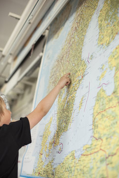 Low angle view of boy pointing on map in classroom