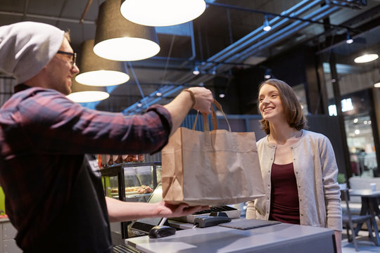 seller giving paper bag to customer at vegan cafe