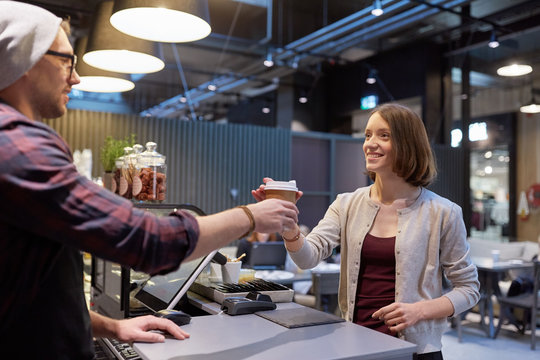 seller giving coffee cup to woman customer at cafe