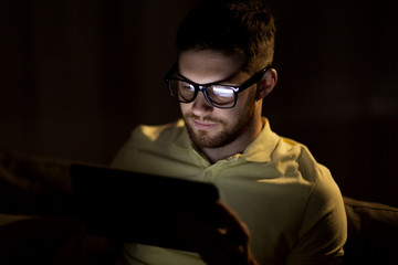 young man with tablet pc networking at night