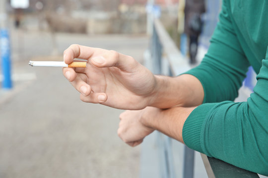 Male hand holding cigarette, closeup