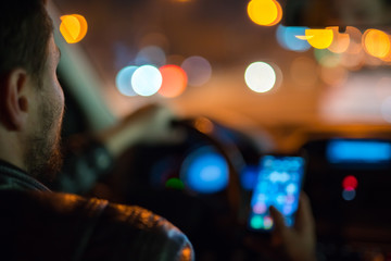 The man phone inside a modern car in the city. Evening night time