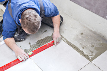 Tiling Floor & Wall. The tiler builder arranges the bathroom ceramics.  Laying tiles on the floor