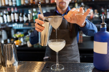 barman with shaker preparing cocktail at bar