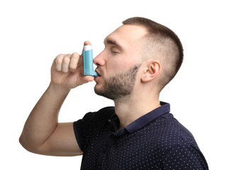 Young man using asthma inhaler on white background