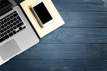 Laptop, smart-phone and notebook on blue wooden table