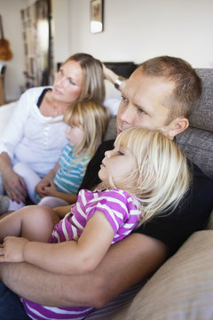 Family sitting on sofa in living room at home