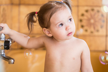 Little girl in bathtub with soap bubbles