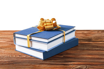 Stack of books with ribbon as gift on wooden table