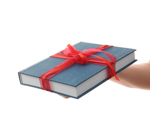 Woman holding book with ribbon as gift on white background