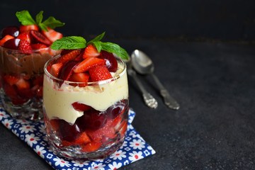 dessert with strawberries and cream in a glass on a black background concrete