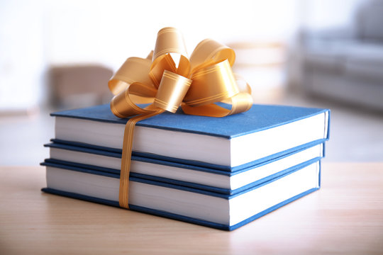 Stack Of Book With Ribbon As Gift On Wooden Table