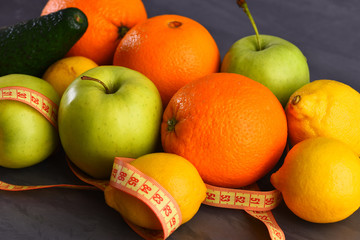 various fruits: lemon, apple, orange, avocado, grey studio wall background