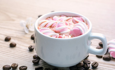 Mug of hot coffee with marshmallows on a wooden background