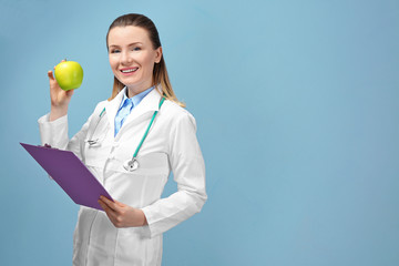 Young female nutritionist on light color background