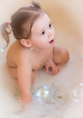 Playing with bubbles.Happy little girl in bathtub playing with soap bubbles