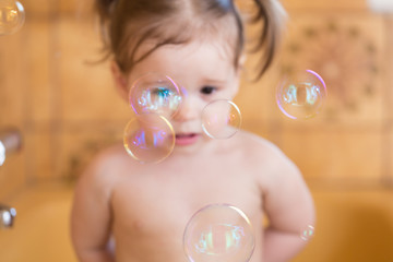 Catching soap bubbles.Adorable little girl in bathtub trying to catch soap bubbles