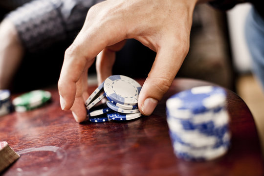 Cropped image of hand holding poker chips at casino