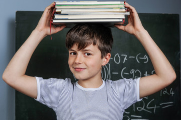 Schulkind mit Schulbüchern vor einer Tafel