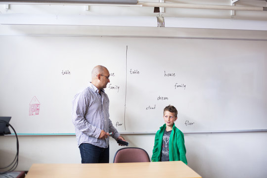 Teacher talking to schoolboy in classroom