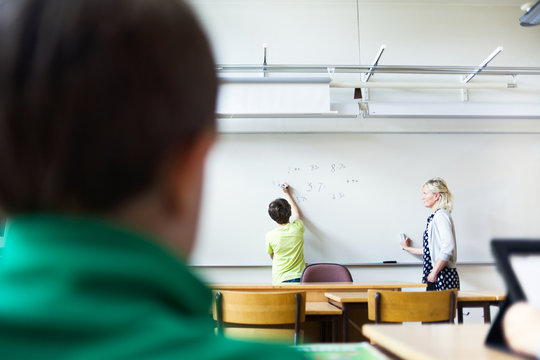 Teacher assisting student in solving mathematics in classroom