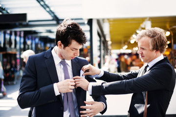 Businessman adjusting colleague's pocket square while standing outdoors