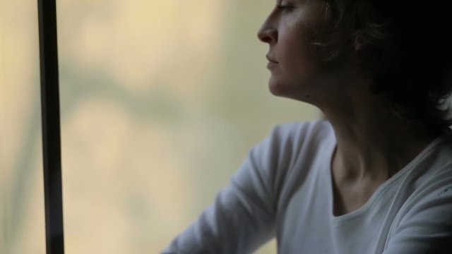Sad woman near window thinking about something, Female broken-hearted
