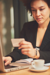 Young African american girl using credit card for paying bills online