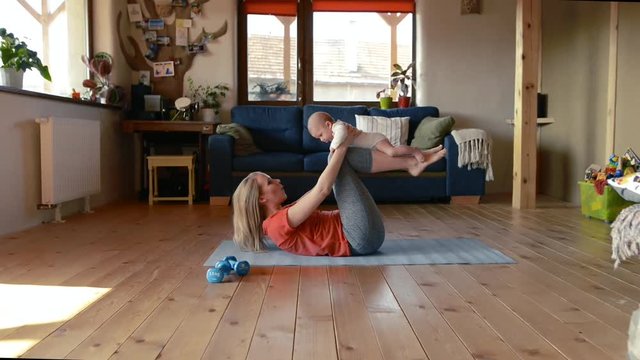 Mother does fitness with her little baby at home.