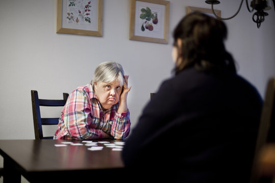 Mature woman with down syndrome looking at friend while sitting in nursing home