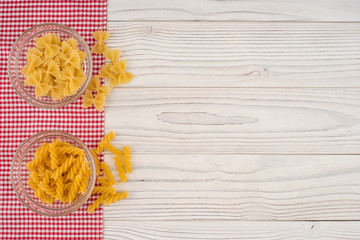 Pasta in a glass bowl on the old wooden table.