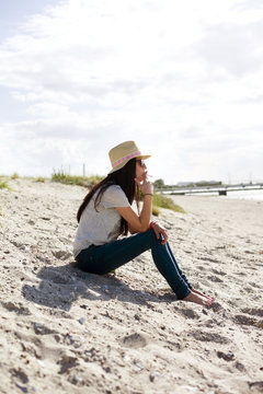 Full length side view of young woman smoking at beach