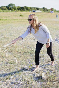Full length of young woman playing kubb on field