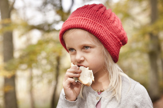 Girl eating bread outdoors