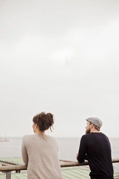 Rear view of business people standing on building terrace by river against clear sky