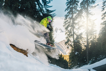 snowboarder with special equipment is riding and jumping very fast in the mountain forest