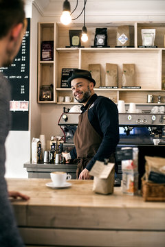 Happy mid adult barista preparing coffee for customer at cafe