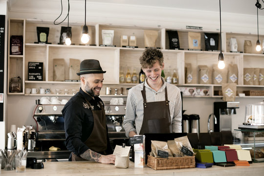 Smiling male baristas working at counter in coffee shop