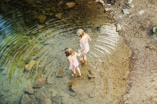 High angle view of girls holding hands while entering lake
