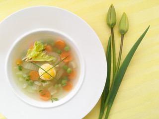 Vegetable spring soup. Easter soup with carrot, peas, celery and egg. Top view.
