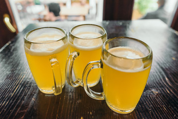 Three cups of beer on the wooden table in the pub