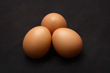 Three chicken eggs on a black background. Close up