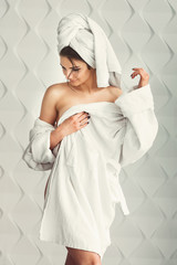 sexy young girl with dark hair, big eyes and dark eyebrows wearing white bath robe whith towel on...