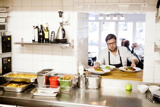 Chef holding serving dishes at commercial kitchen counter