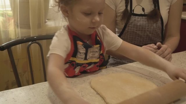 The girl with her mother rolled out the dough with a rolling pin