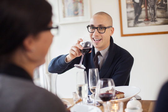 Happy man having red wine while talking to friend at restaurant